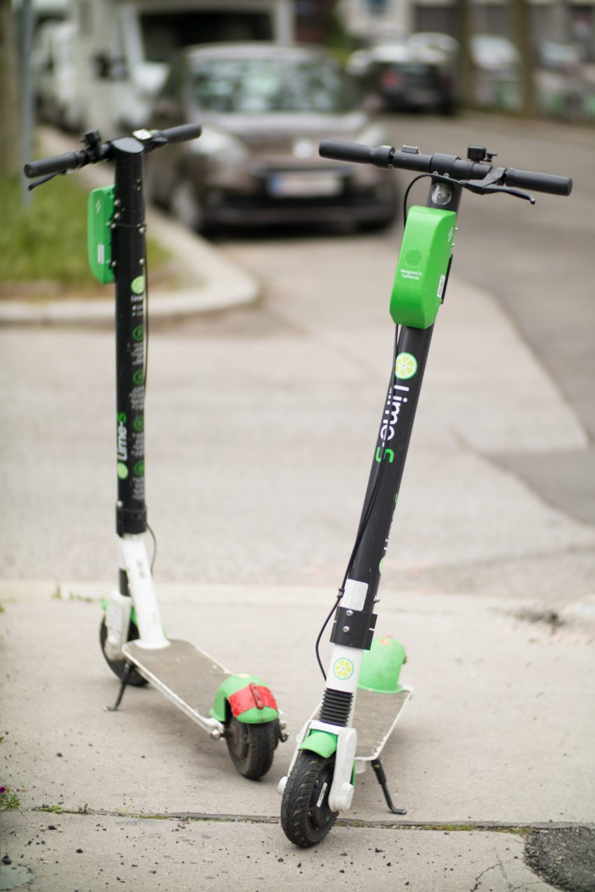 Two e-scotters parked on a sidewalk